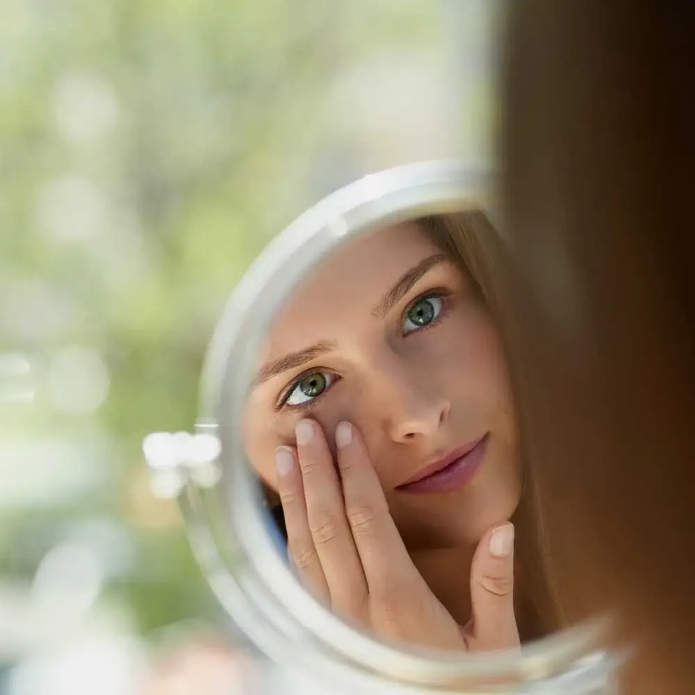 young woman checking her face on the mirror