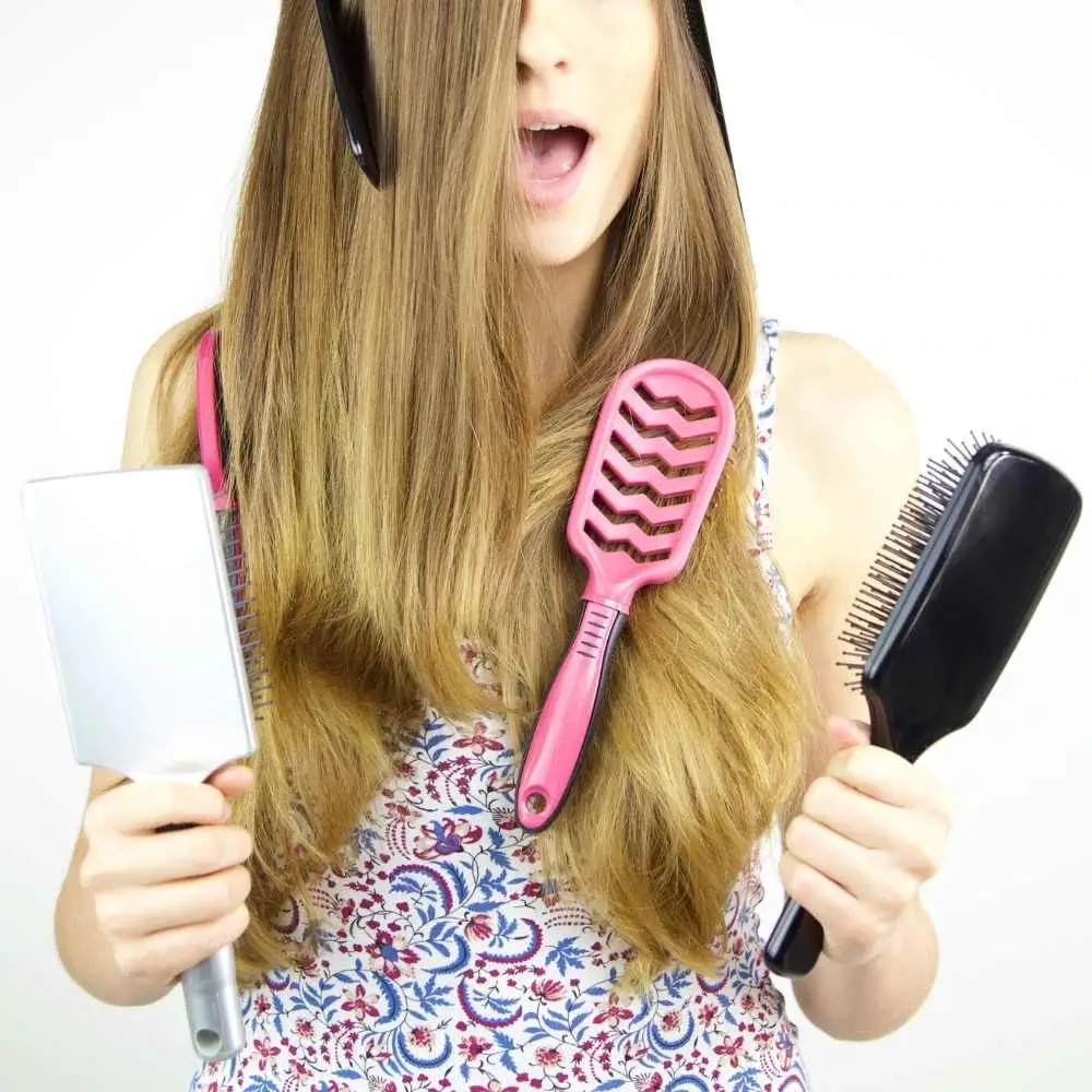 woman holding hair brushes with hair brushes on her hair