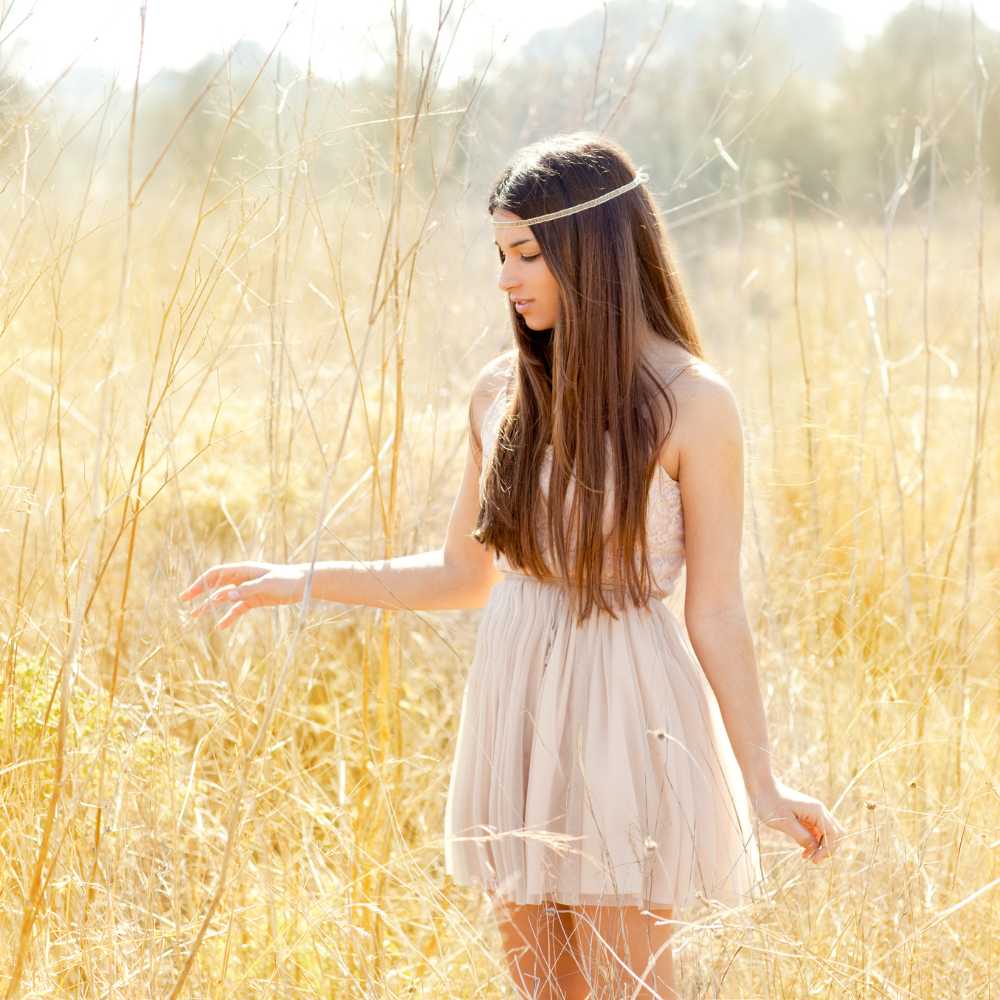 teenage girl in the middle of golden driend grass field