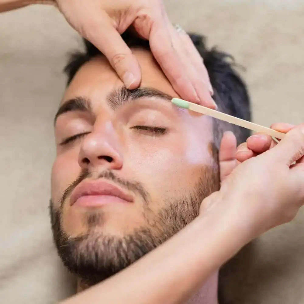 young man with a beard getting his eyebrows waxed