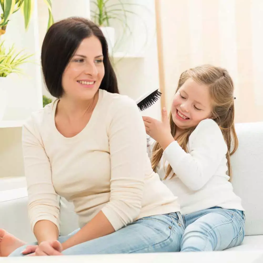 little girl combing her mother's hair