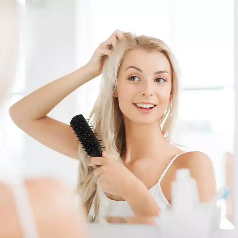 blonde woman combing her hair in front of the mirror