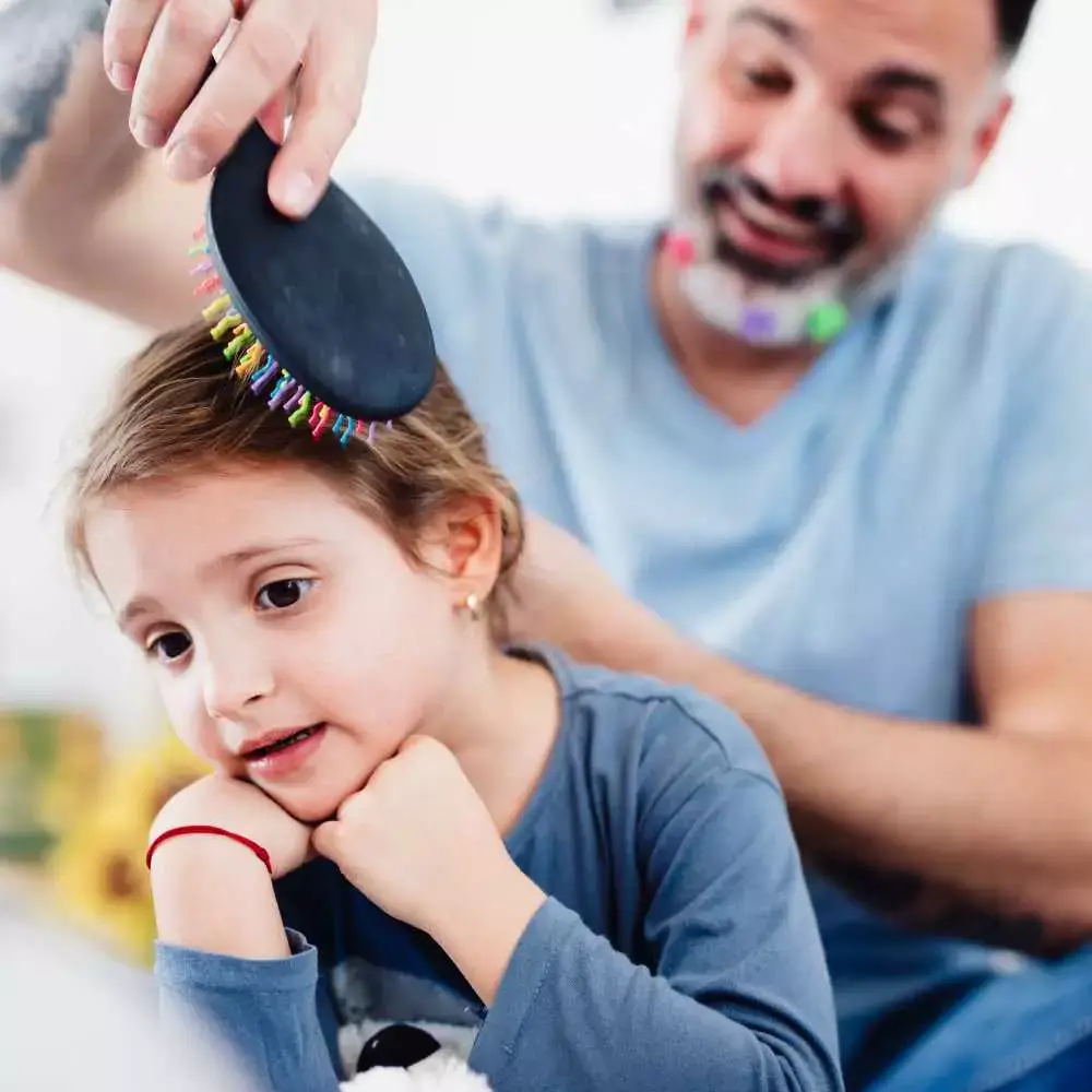 a father comnbing her daughter's hair with a colorful hair brush