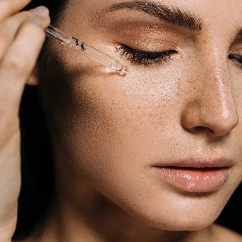 Person applying Vitamin C serum on face for brighter, healthier skin