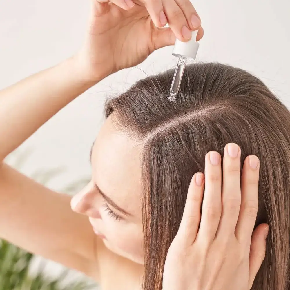 A user applying pure argan oil to promote healthier hair