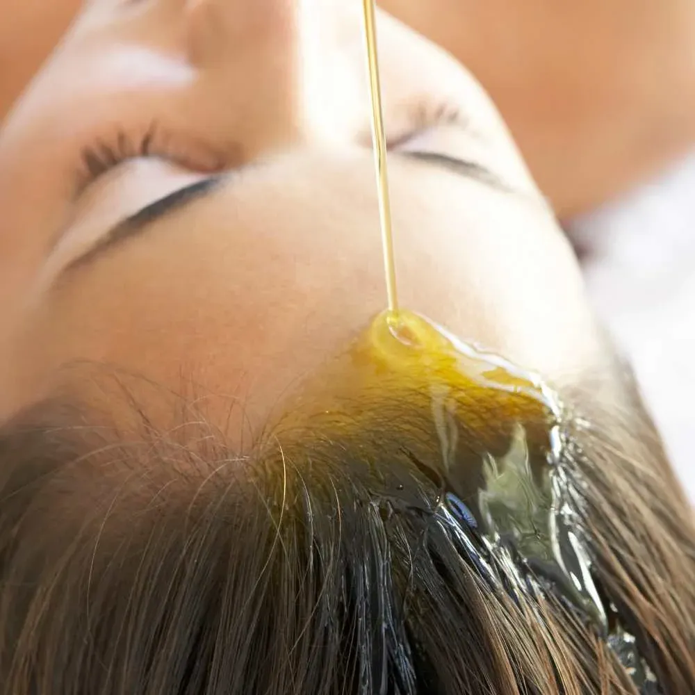 Close-up image of golden Argan Oil being poured onto hair