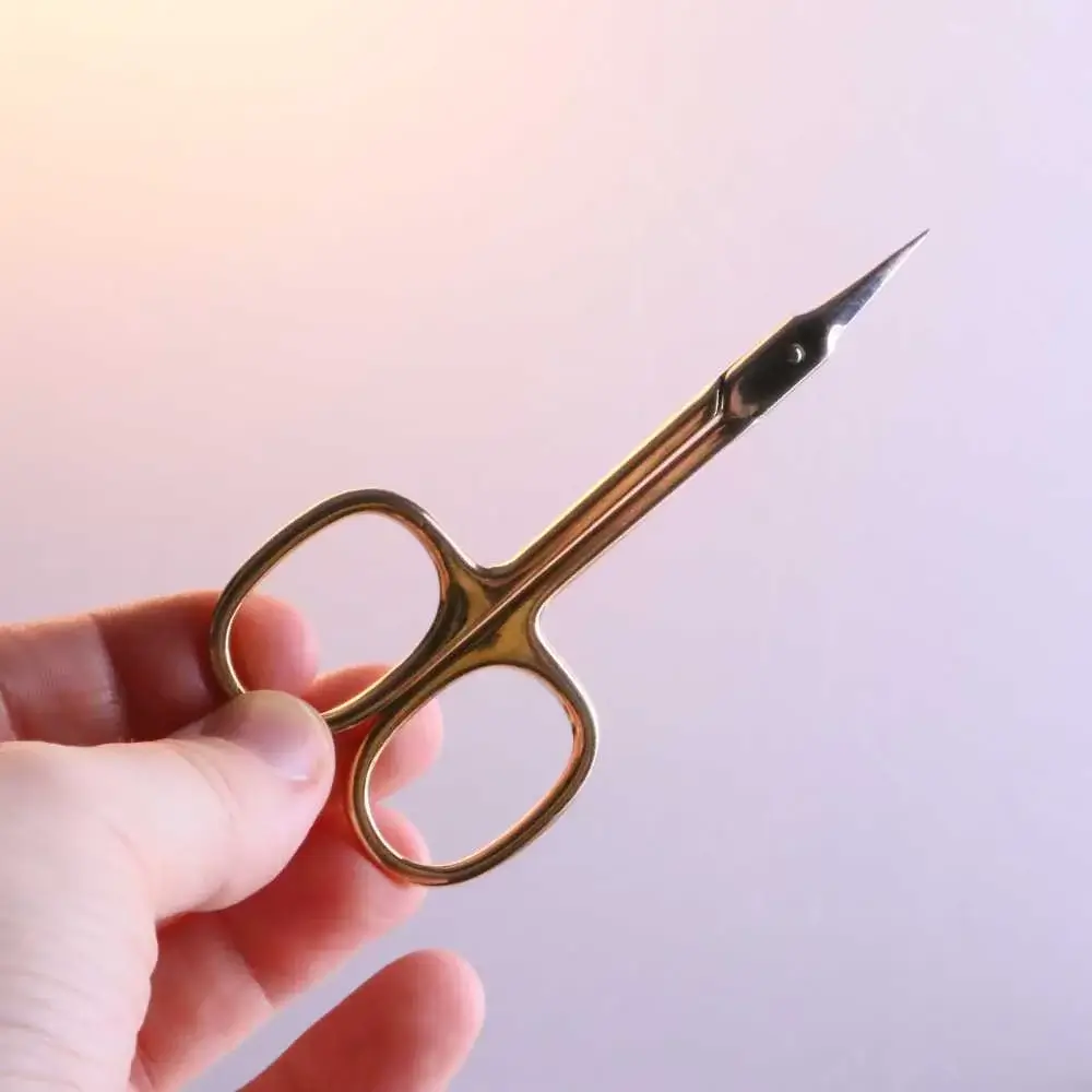 Hands holding eyebrow scissors to trim eyebrows