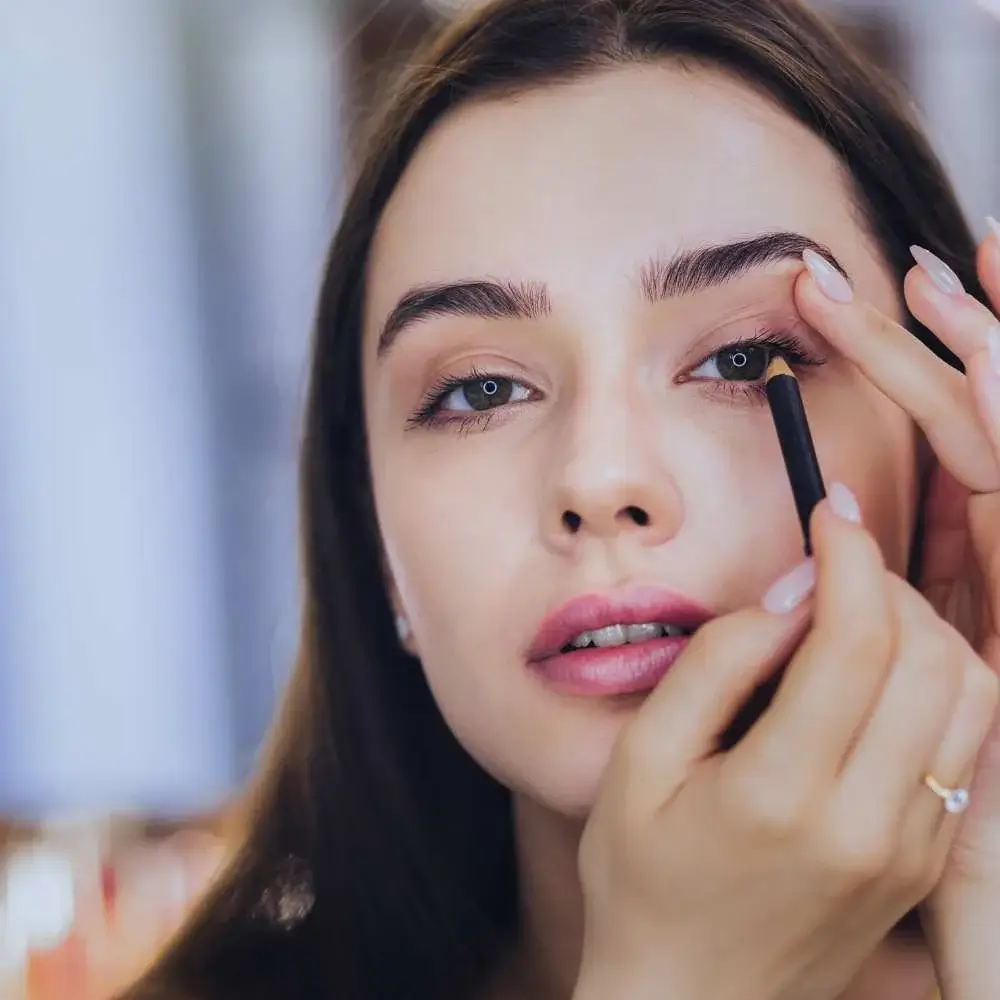 A woman applying vibrant, water-activated eyeliner for a bold look