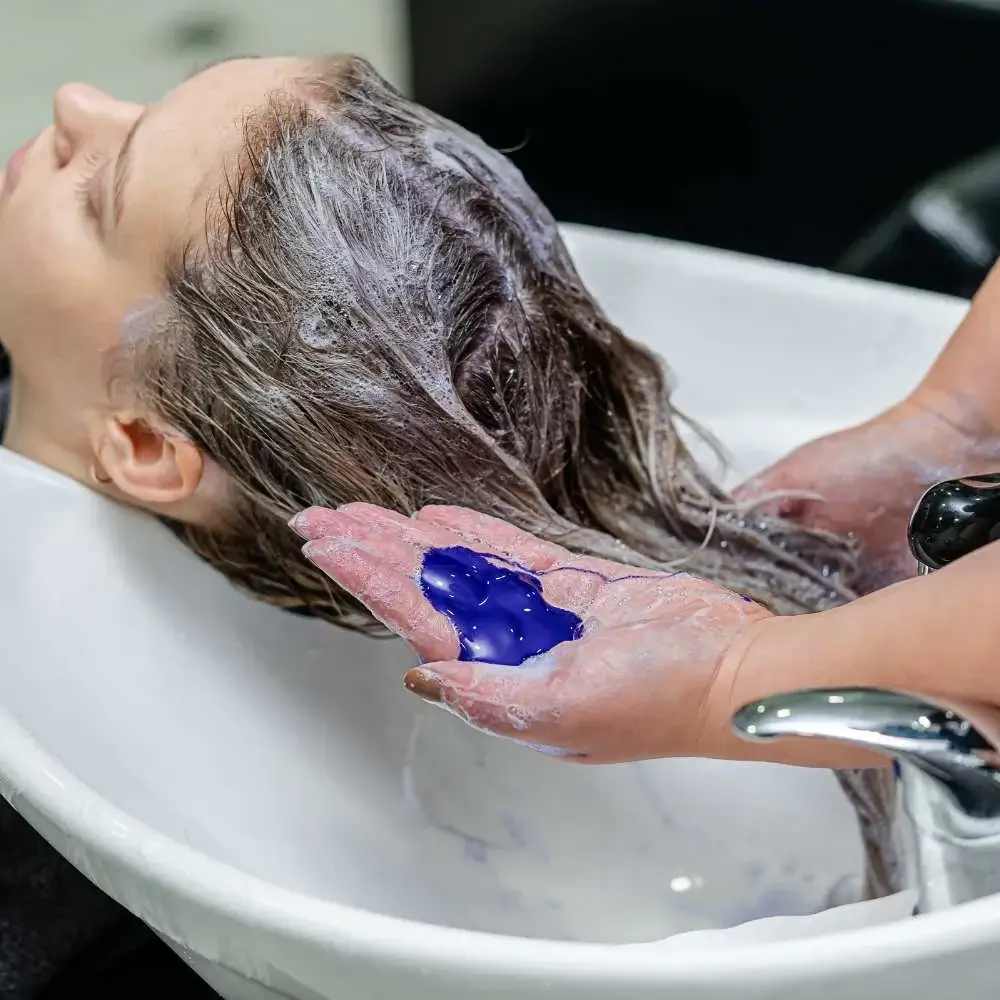 Person pouring shampoo for blonde hair onto hand, ready for application