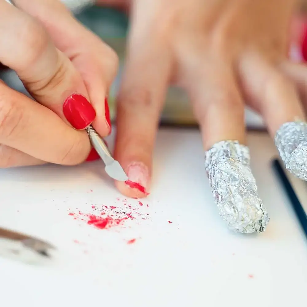 Woman carefully peeling off old nail polish