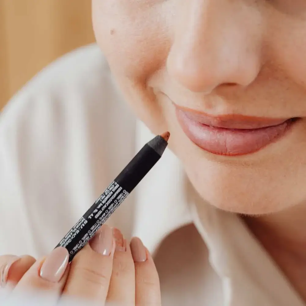 A woman precisely applying a red lip liner for a bold look