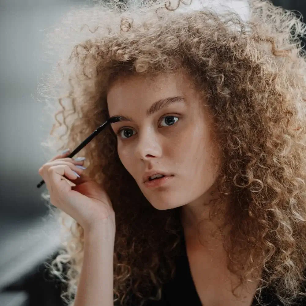 Woman applying the best eyebrow pomade with a precision brush for a natural look