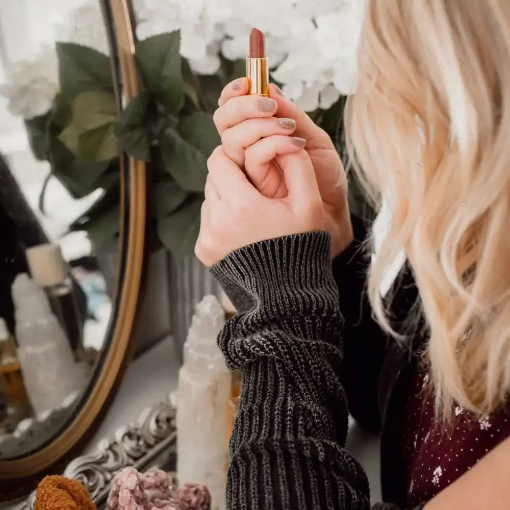 Hand holding up a tube of vibrant red cruelty-free lipstick