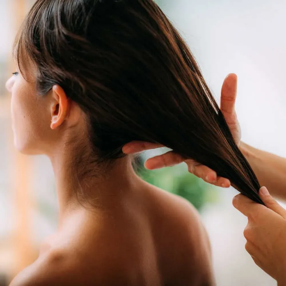 Person applying Argan Oil to their hair, demonstrating its hydrating benefits