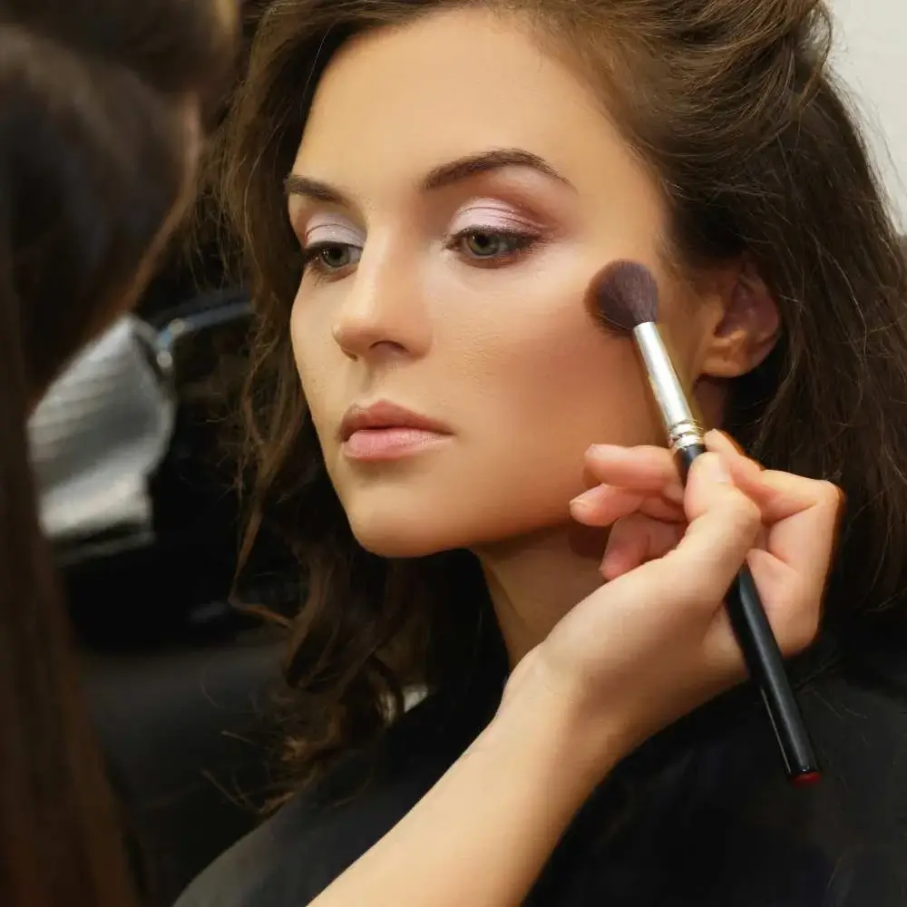 Woman applying bronzer with a fluffy makeup brush