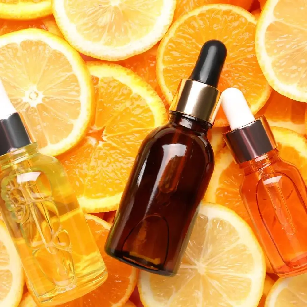 A bottle of Vitamin C serum placed against a fresh citrus background
