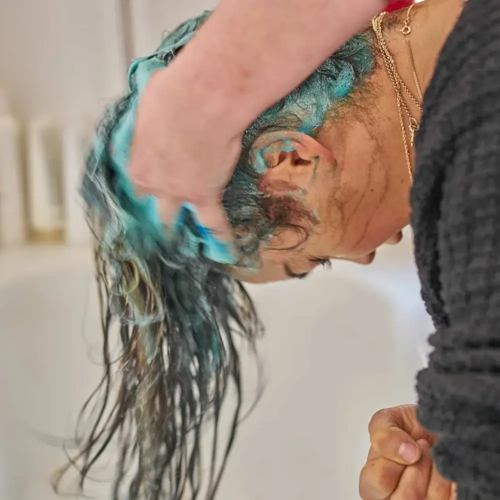 Lathered blue shampoo on hair, working to reduce brassiness