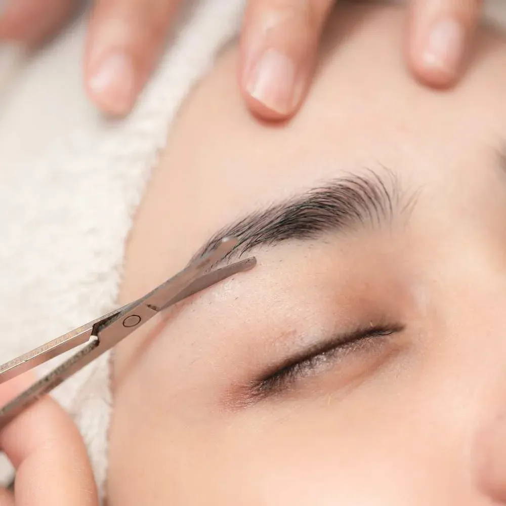 trimming their eyebrows with scissors