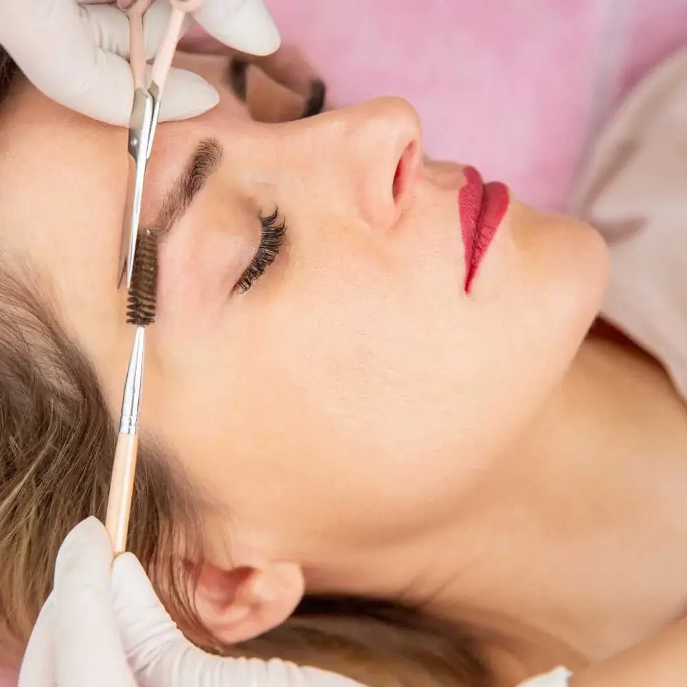 Aesthetician carefully trimming eyebrows with scissors