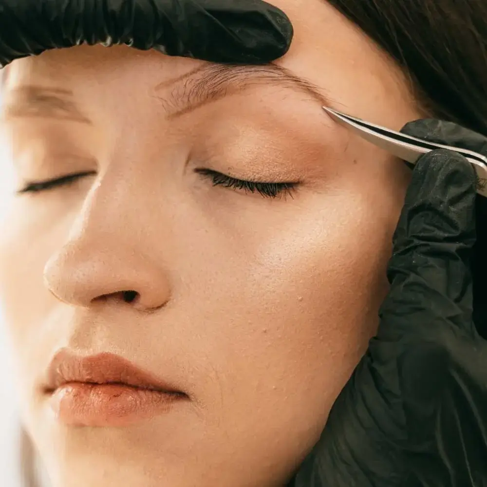 Woman using a pair of eyebrow tweezers for shaping her brows