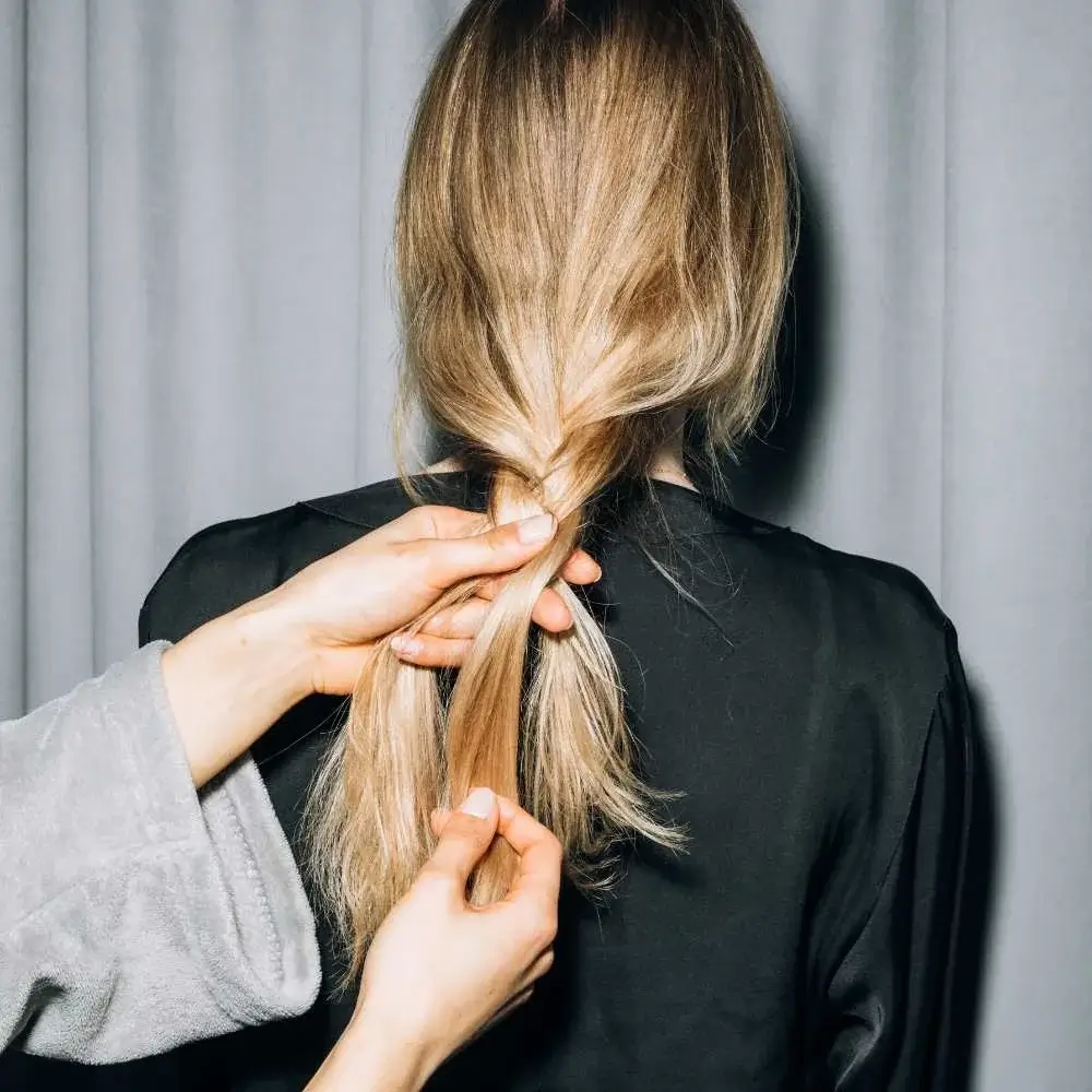 A blonde woman displaying her glossy hair after using blonde hair shampoo