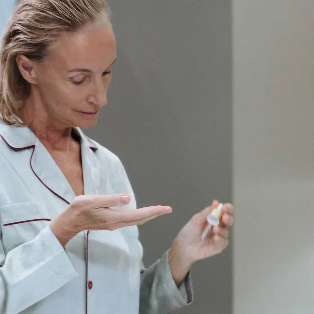 Woman applying best face primer on her mature skin