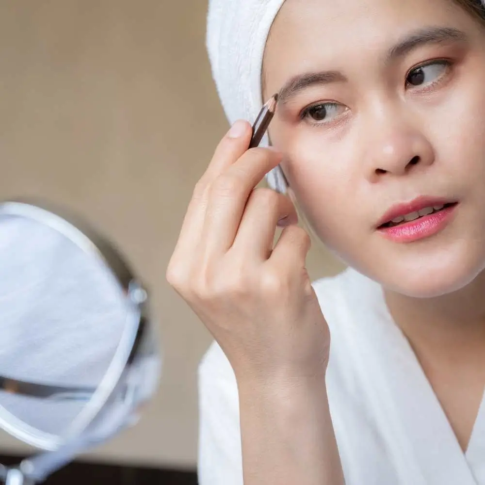 A woman confidently using her waterproof eyebrow pencil