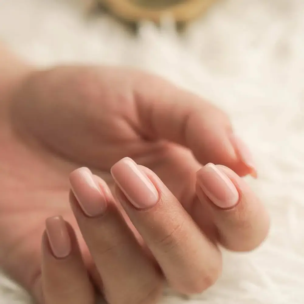 A close-up of perfectly painted nails in a sophisticated nude shade