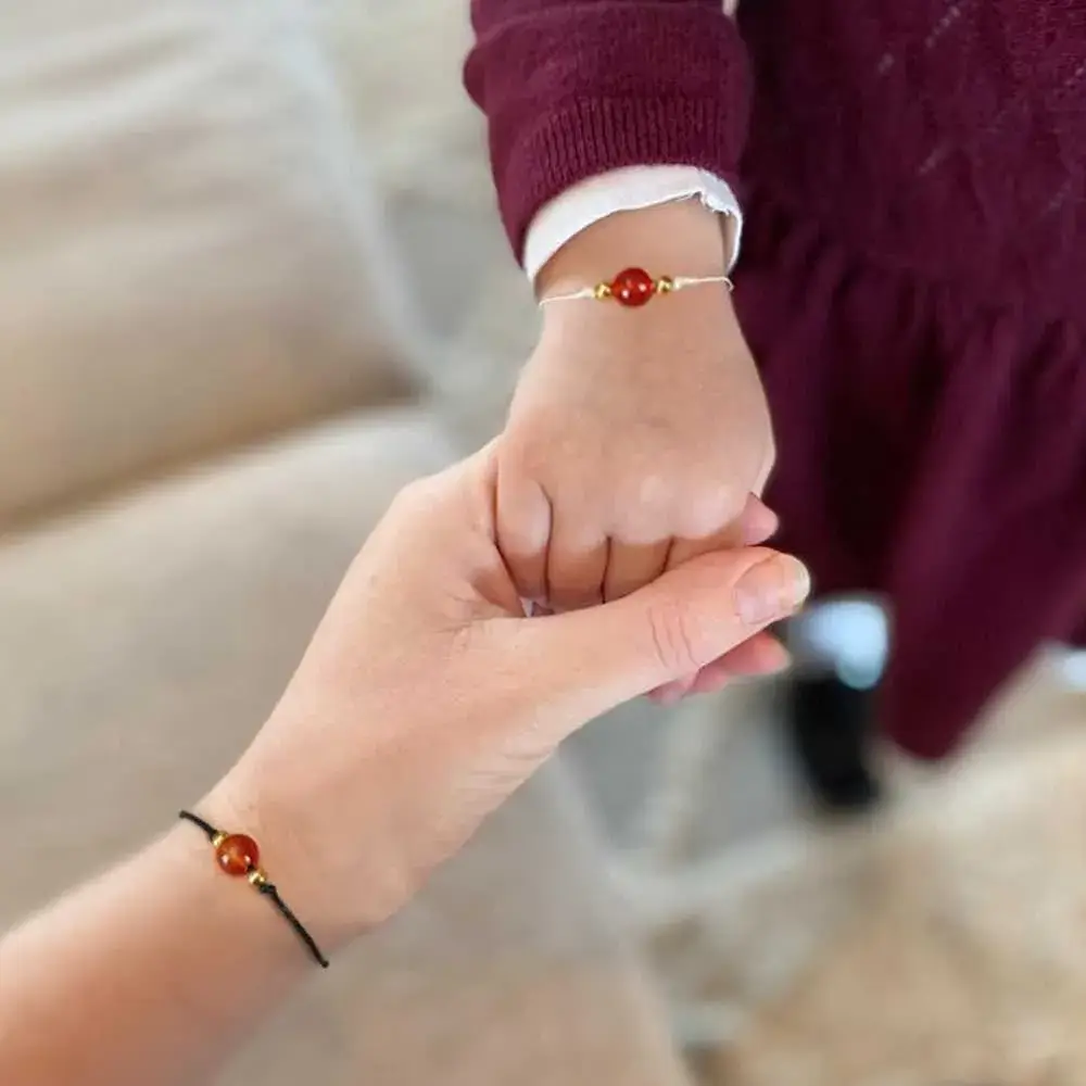 hands of a child and a mother wearing carnelian crystal bracelets