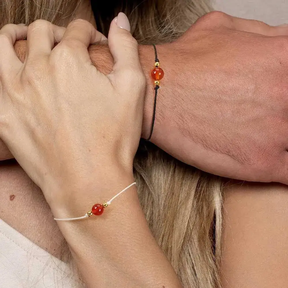 hands of a man and a woman wearing carnelian crystal bracelets
