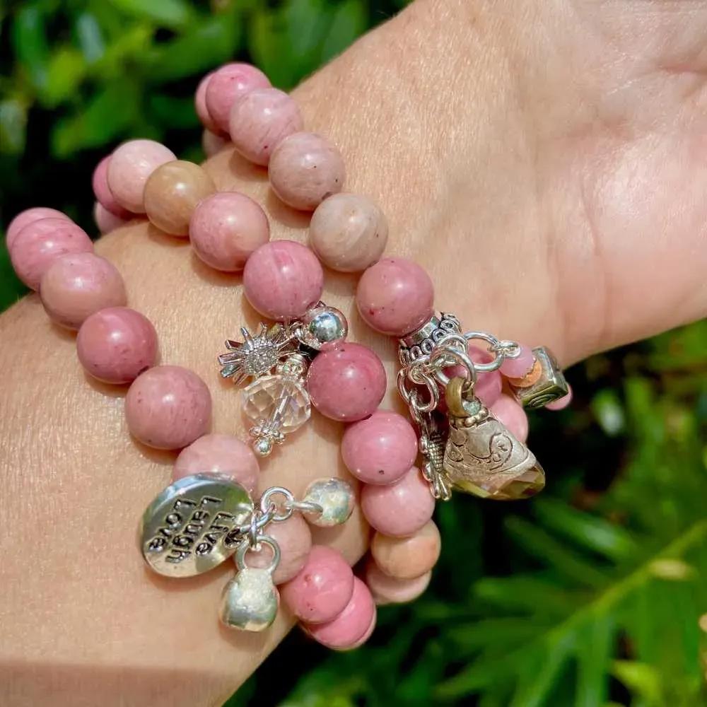 close-up view of a wrist wearing rhodonite bracelets with silver accents