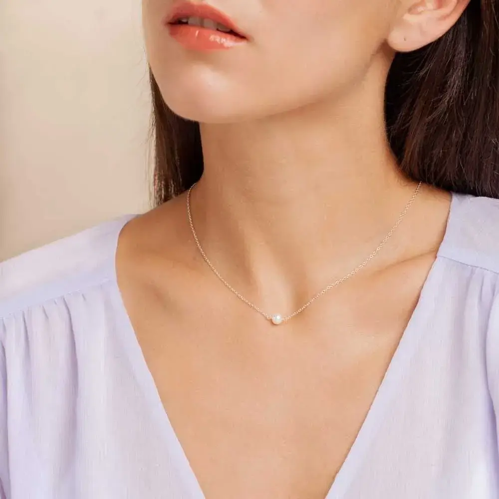 close-up portrait of a woman's neck with tiny pearl necklace