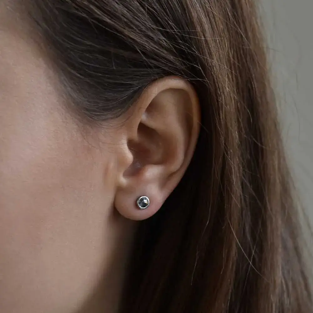 close-up of a woman's ear with salt and pepper diamond stud earring