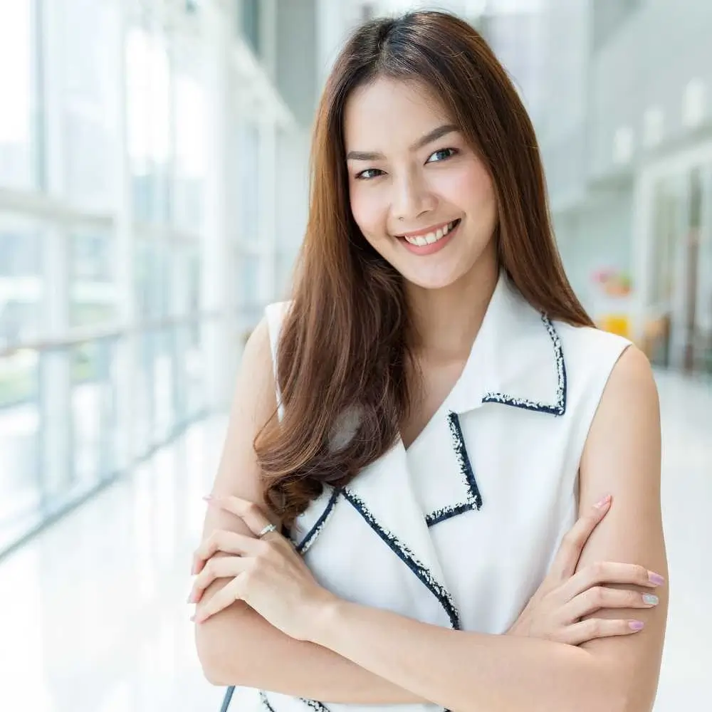 smiling asian woman wearing a white dress with curled brown hair