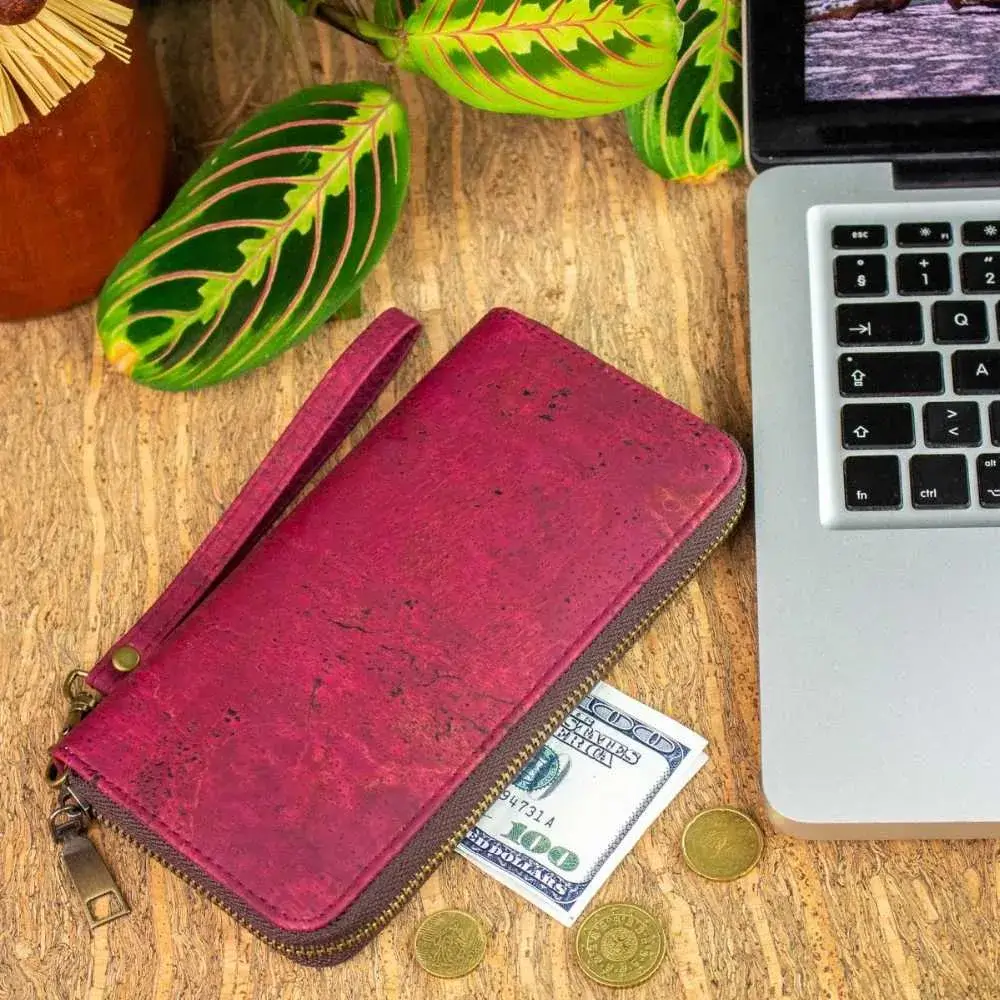 red cork wallet and money beside a laptop