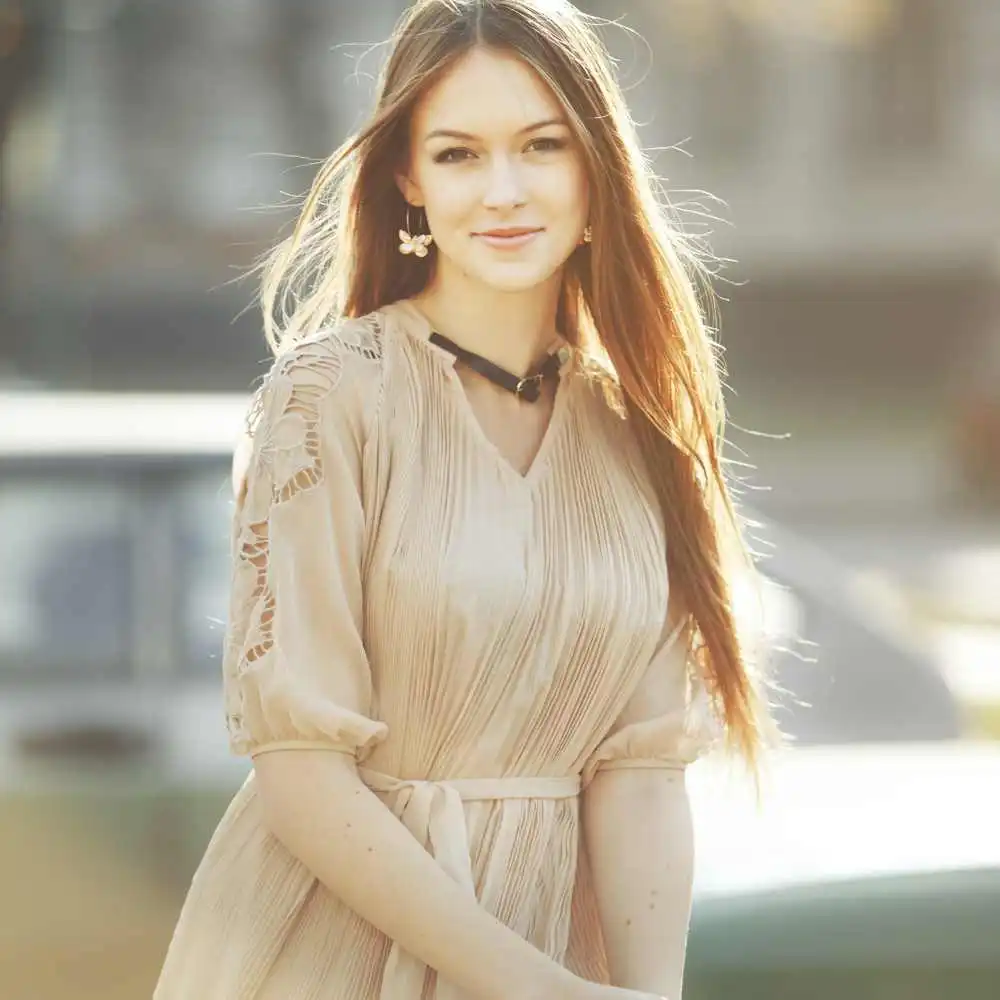 brunette woman with long straight hair wearing a dress outdoors
