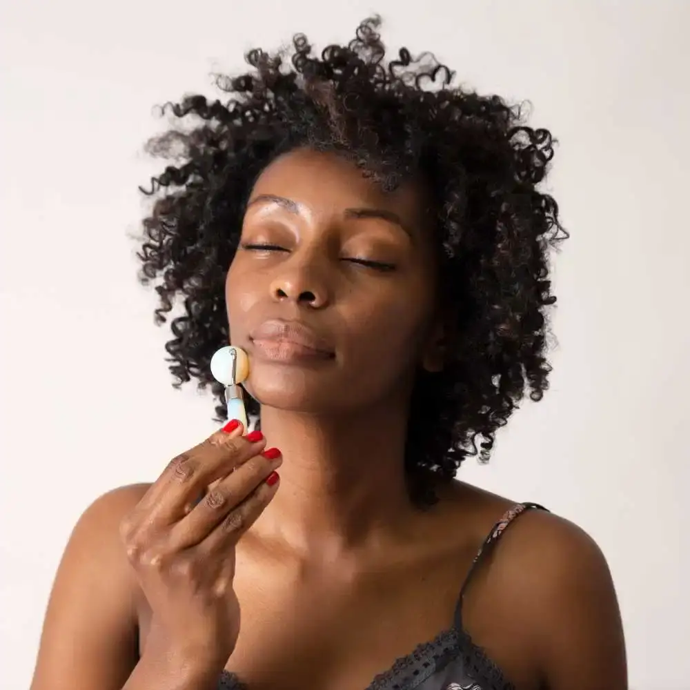 woman with curly hair using white face roller