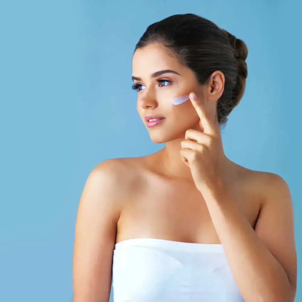 young woman applying face moisturizer