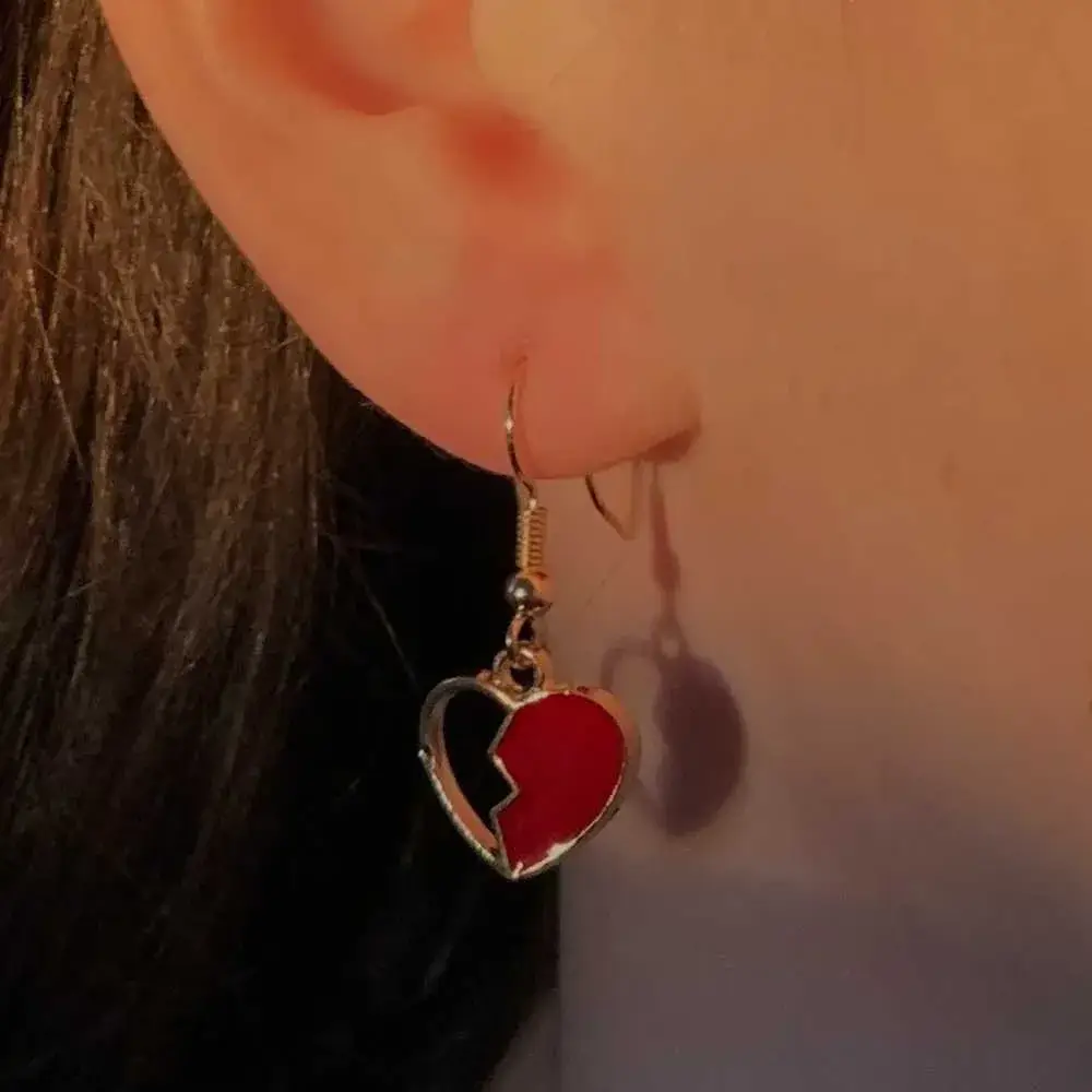 close-up view of a woman's ear with red broken heart earring