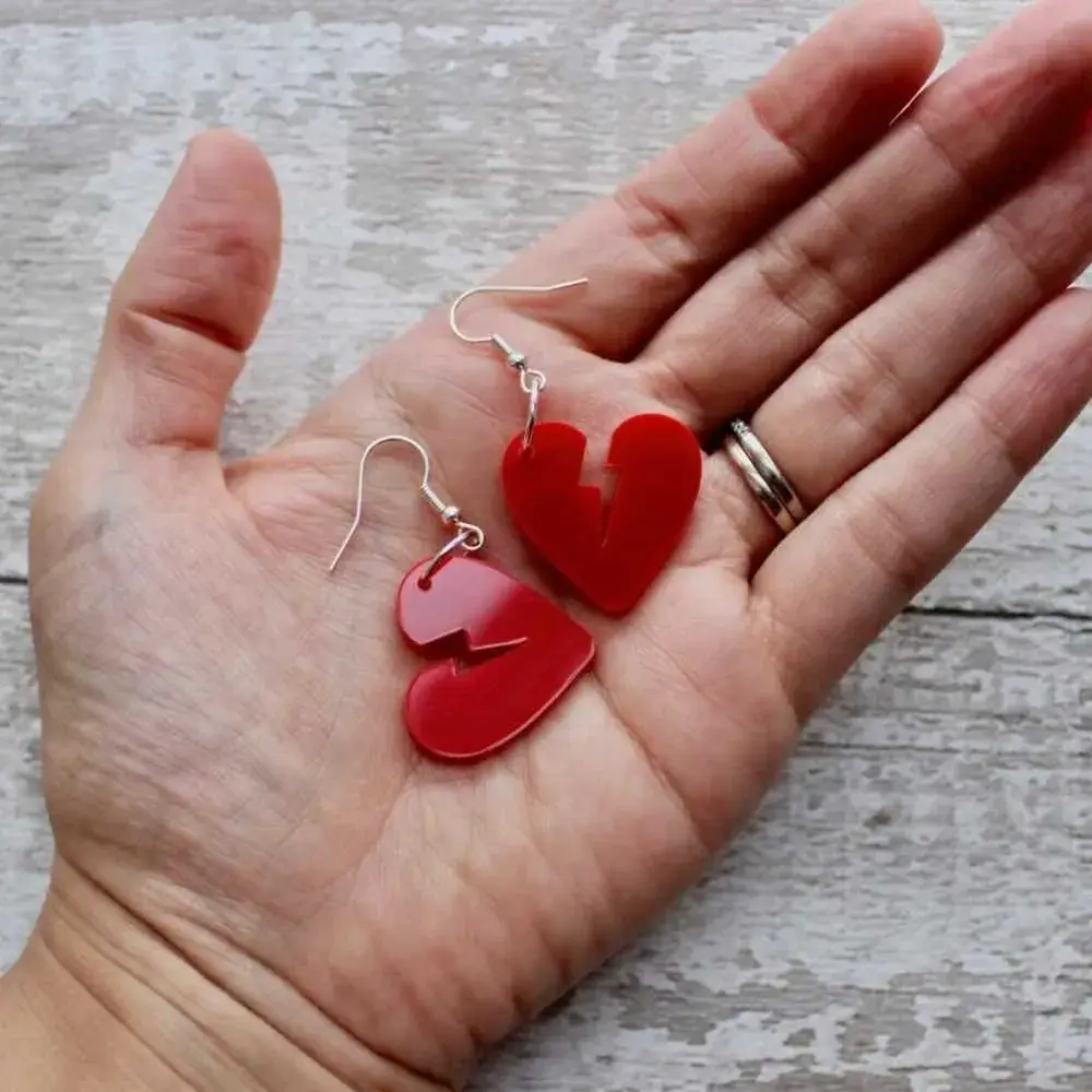 red broken heart earrings on the palm