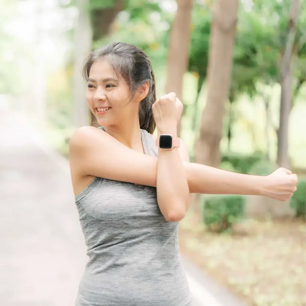 young asian woman wearing a smartwatch exercising outdoors