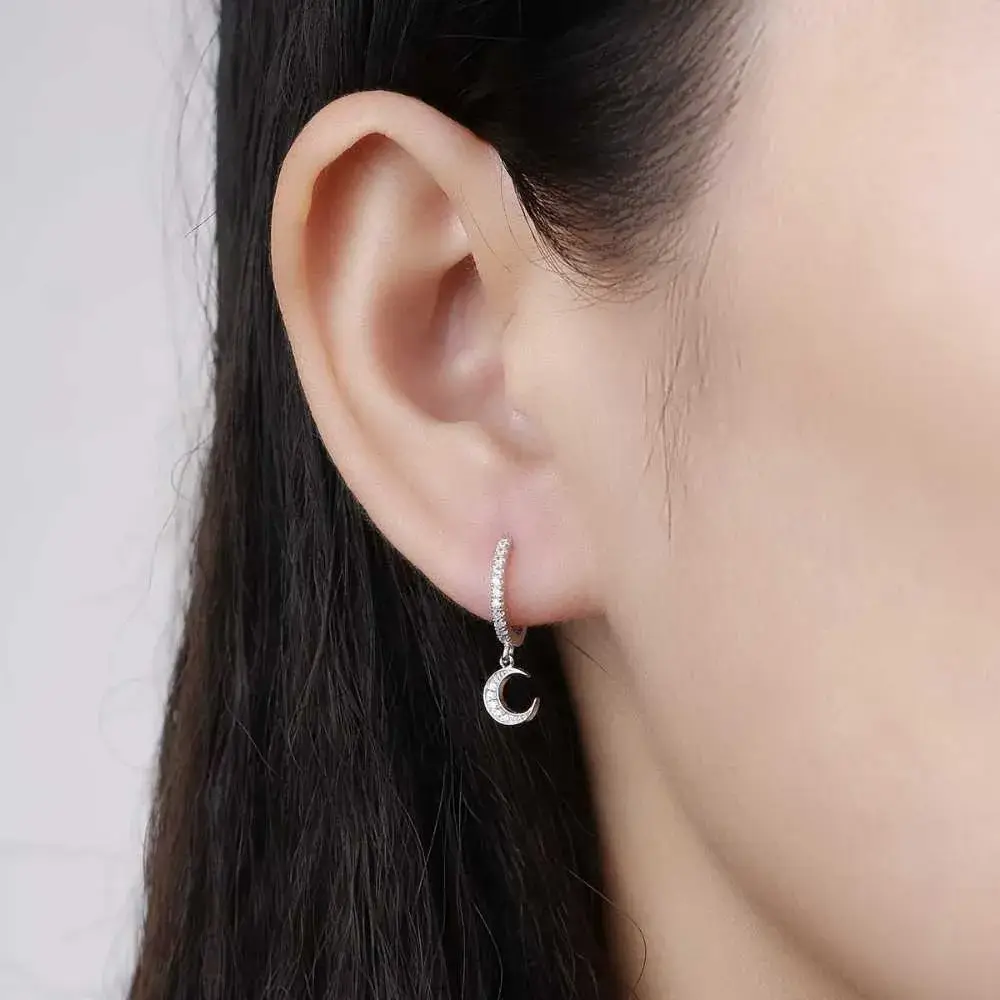 close-up view of a woman's ear with a moon hoop dangle earring