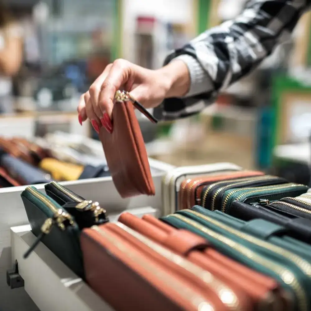 closeup of woman's hands choosing a wallet on the shelf