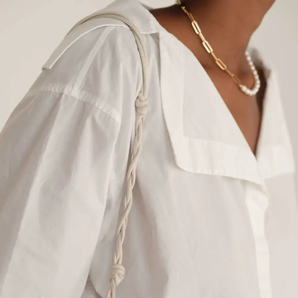 side view of a woman's neck with half chain half pearl necklace