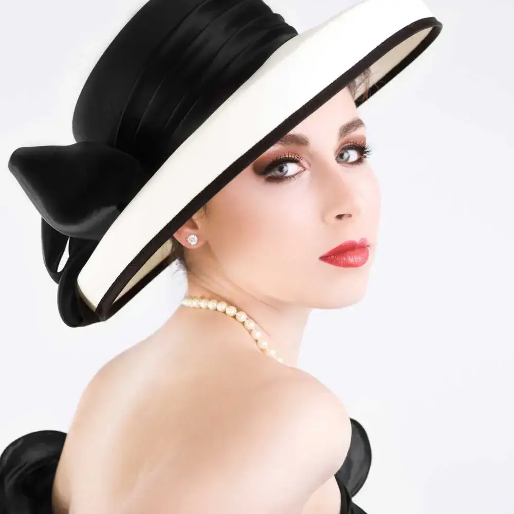 portrait of an elegant young woman wearing pearl necklace and a black hat