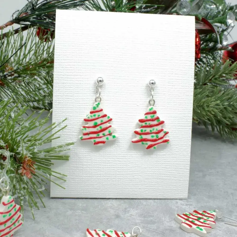 christmas tree cake earrings hooked on a white board