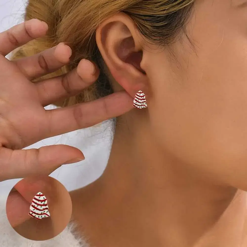close-up view of a woman's ear with christmas tree cake earring