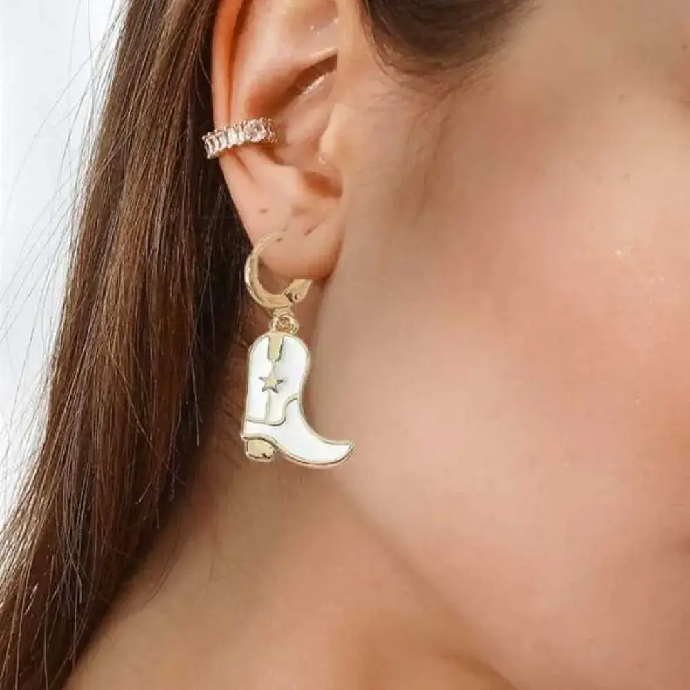 close-up view of a woman's ear with white cowgirl boots earring