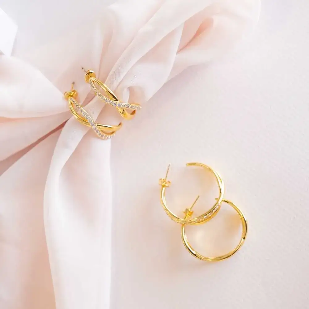 two pairs of golden hoop earrings with small crystals
