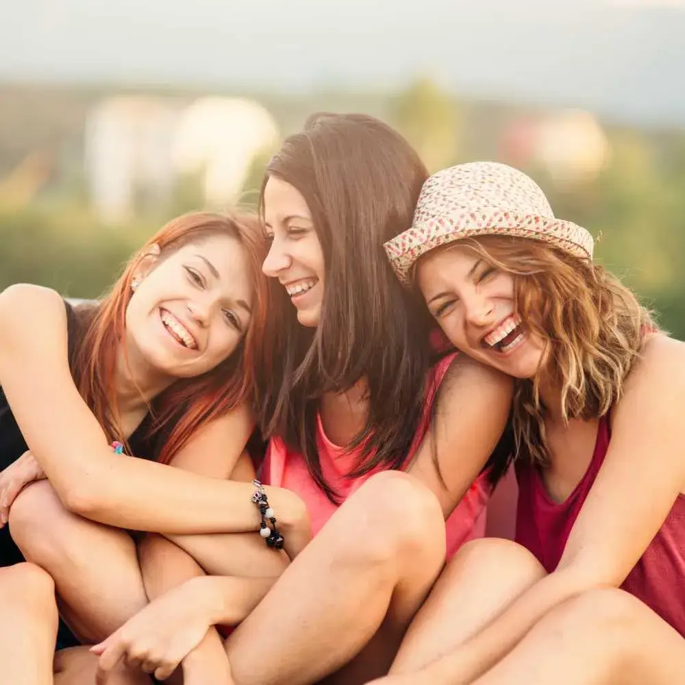 Three young women hugging and laughing